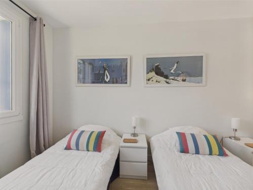 une chambre avec deux lits et deux tableaux au mur dans l'établissement Vue mer - Appart pour 4 - Grand balcon, à Pornichet