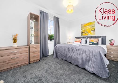 a bedroom with a king sized bed and a dresser at Broomfield Apartment by Klass Living Airdrie in Airdrie