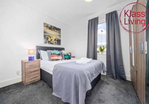 a bedroom with a bed and a dresser and a window at Broomfield Apartment by Klass Living Airdrie in Airdrie