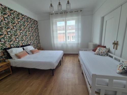 une chambre avec deux lits et une fenêtre dans l'établissement Appartement en centre-ville à 5mn de la plage, à Calais