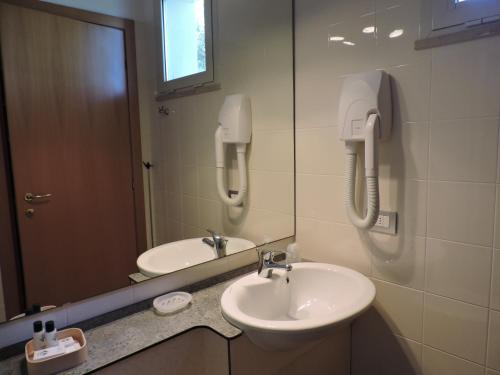 bagno con lavandino, specchio e telefono di Hotel Il Pino a San Vincenzo