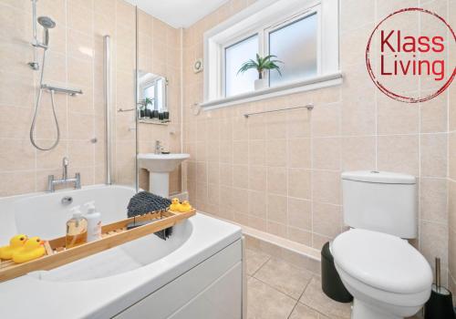 a bathroom with a tub and a toilet and a sink at Coats Street Apartment by Klass Living Coatbridge in Coatbridge