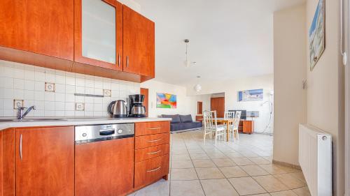 a kitchen with wooden cabinets and a living room at Promenada I, Sun & Snow in Świnoujście