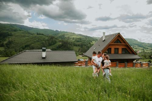 a family standing in a field in front of a cabin at Chata Azarka in Beňuš