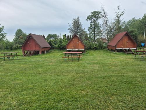 a group of three barns with picnic tables in a field at SZAŁASY drewniane nad rzeką BIEBRZA in Goniadz