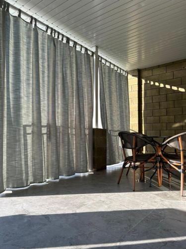 a table and a chair on a patio with curtains at Yssyk-kul Palm in Chok-Tal