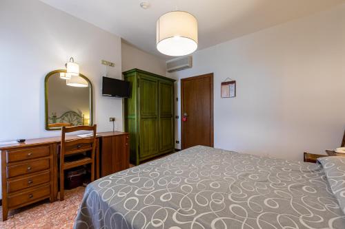 a bedroom with a bed and a dresser and a mirror at Hotel Bisesti ***S in Garda