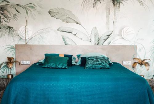 - une chambre dotée d'un lit bleu avec des plantes sur le mur dans l'établissement Villa Nais B&B, à Bormes-les-Mimosas