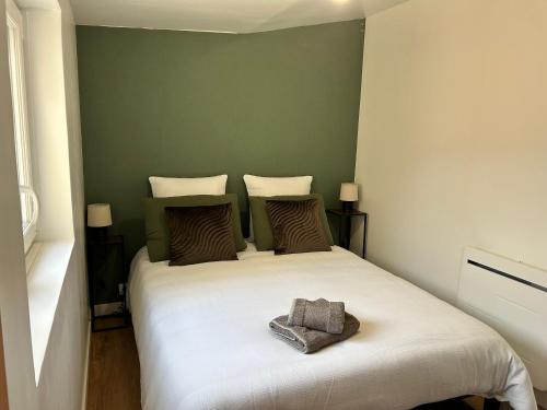 une chambre avec un lit blanc avec un mur vert dans l'établissement La Perle Rive Gauche, au Mans