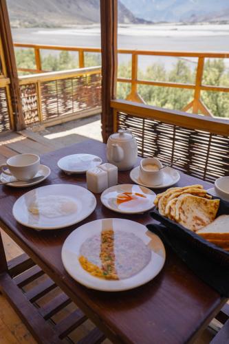 a wooden table with plates of food on it at Dera Lamsa Resort Shigar in Shigar