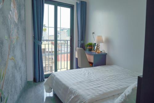 a bedroom with a bed and a desk and a window at Lilo's Homestay West Lake Thuy Khue in Hanoi