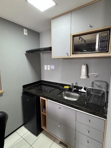 a kitchen with a sink and a microwave at Flat 706 próximo à praia - Condomínio Biarritz in São Luís