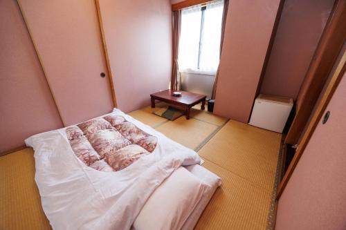 a small room with a bed and a window at ビジネスホテル寿屋 in Handa