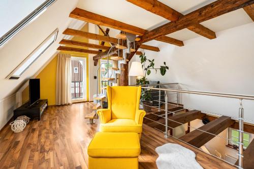 a yellow chair in a living room with wooden ceilings at Ferienhaus Oberlausitz mit 160qm in Cunewalde