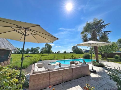 un patio avec des parasols et une piscine dans l'établissement Maison de campagne en Normandie, à Saint-Martin-Saint-Firmin