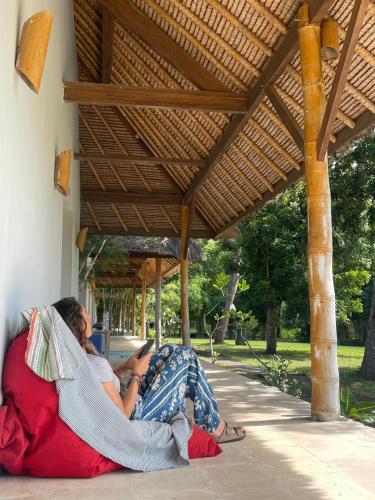 a woman sitting on a couch under a porch at ekasboardriders surf&stay in Ekas