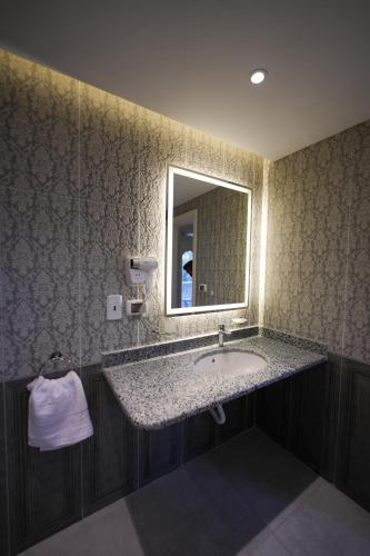 a bathroom with a sink and a mirror at The H Zamalek Suites in Cairo