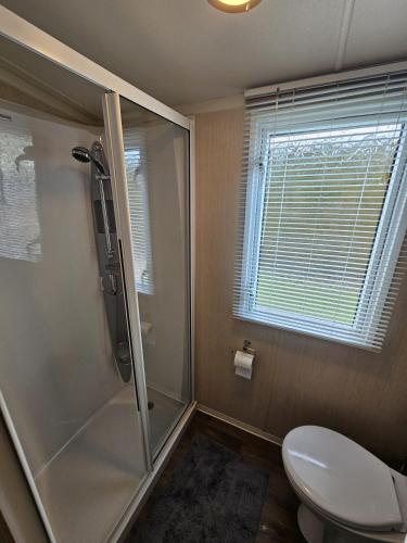 a bathroom with a shower and a toilet and a window at Punchbowl Caravan Park in Penrith