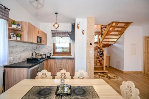 eine Küche mit einem Tisch und Stühlen sowie eine Treppe in der Unterkunft Domek i Apartament pod Tatrami in Suche