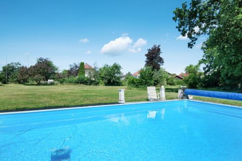 a blue swimming pool with a chair and a yard at Villa Galerie in Hohenwart