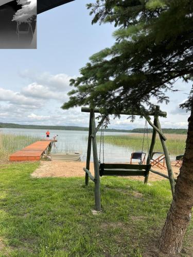 a swing in front of a lake with a dock at Agroturystyka Katarzyna Tarasiewicz in Stary Folwark