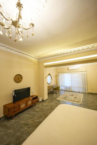 a living room with a television and a chandelier at The H Zamalek Suites in Cairo