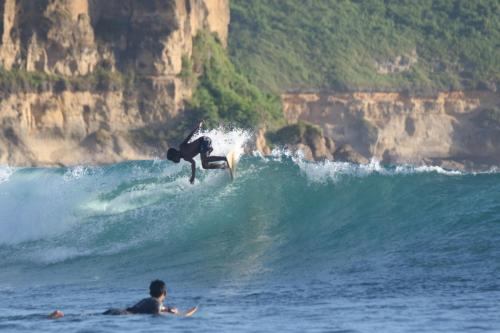 a person riding a wave on a surfboard in the ocean at ekasboardriders surf&stay in Ekas