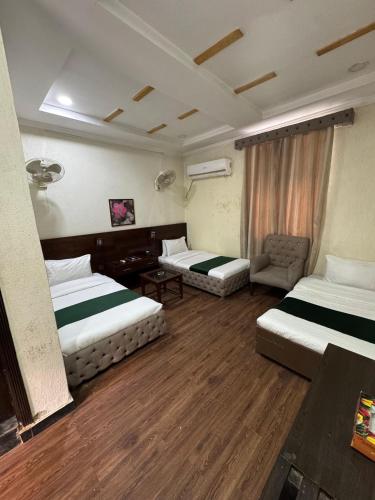 a hotel room with two beds and a chair at Hotel Crescent in Tahkāl Pāyān