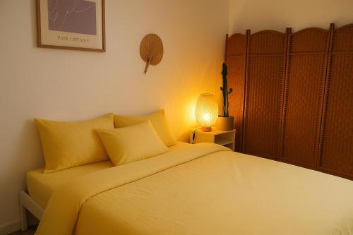 - une chambre avec un lit doté de draps jaunes et d'une lampe dans l'établissement Magnifique T3 Art Deco Ecusson, à Montpellier