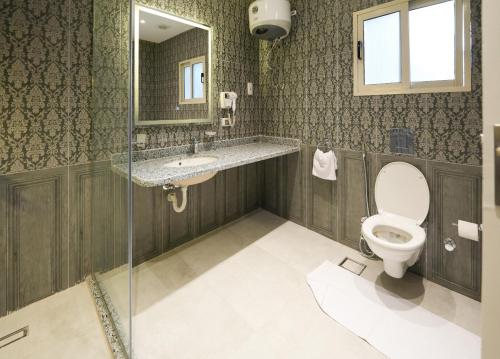 a bathroom with a toilet and a sink and a mirror at The H Zamalek Suites in Cairo