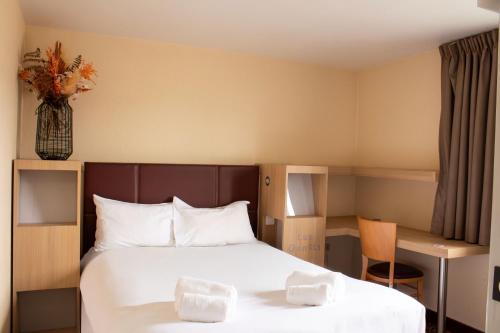 a hotel room with a bed and a desk at Hôtel Les Genêts Bayonne in Bayonne