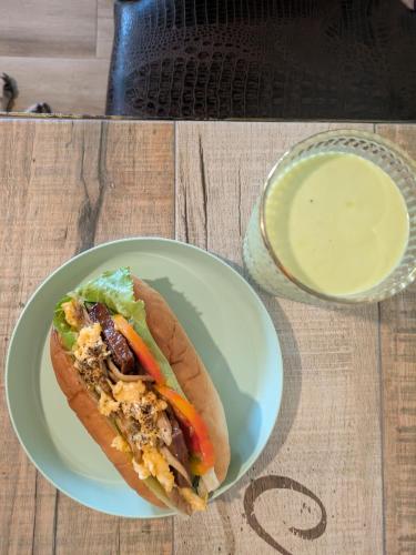 a sandwich on a plate on a table with a drink at Sleep Melon Homestay in Taitung City