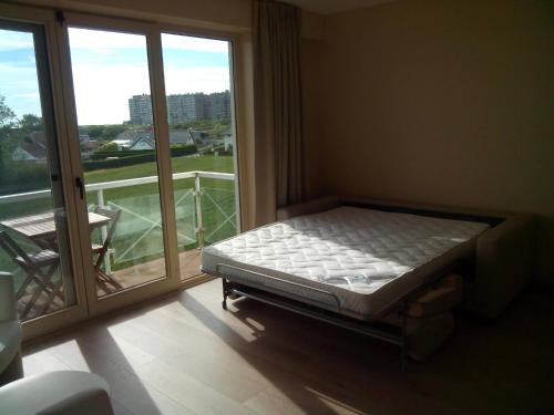 a bed in a room next to a window at Apartment Green Garden Block L in Middelkerke