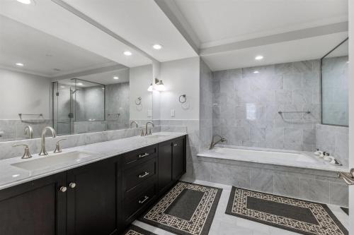 Un baño con dos lavabos, una bañera y una ducha. en Residence 111 At The Grand, en Wildwood