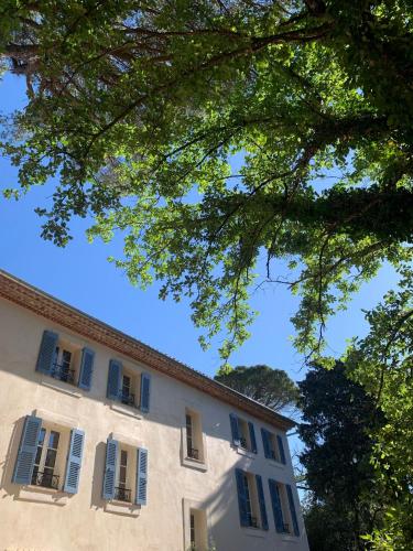 a building with blue shuttered windows and trees at Ferme Saint-Georges en Provence in Le Val