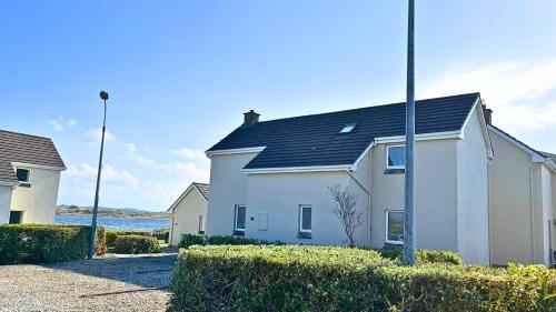 a white house with a black roof at Aillebrack Cottage in Ballyconneely