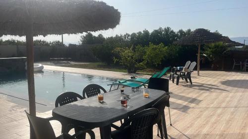 a table with chairs and an umbrella next to a pool at Villa Clémentine piscine privée - 6 pers in Berkawe