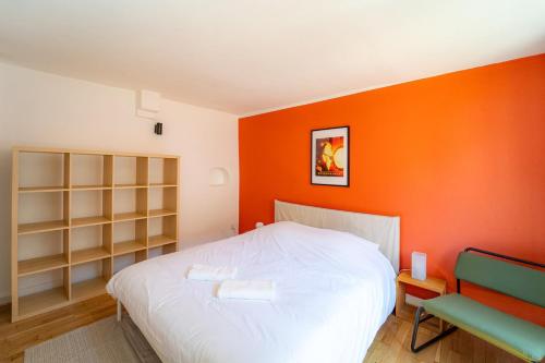 - une chambre avec un mur orange, un lit et une chaise dans l'établissement Gunther - Cocon alsacien au centre ville, à Strasbourg