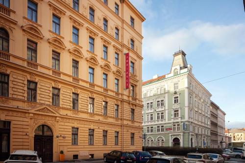 two tall buildings with cars parked in a parking lot at Hotel Ambiance in Prague