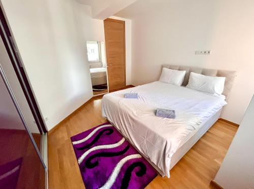 a bedroom with a white bed with a purple rug at Aylin Apartman in Sarajevo