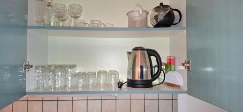 a tea kettle is sitting on a shelf with glasses at Izabella Studios Apartments in Pitsidia