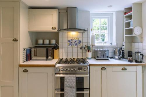 a kitchen with white cabinets and a stove top oven at Danny Lodge - Country Cottage Near Brighton by Huluki Sussex Stays in Hurstpierpoint