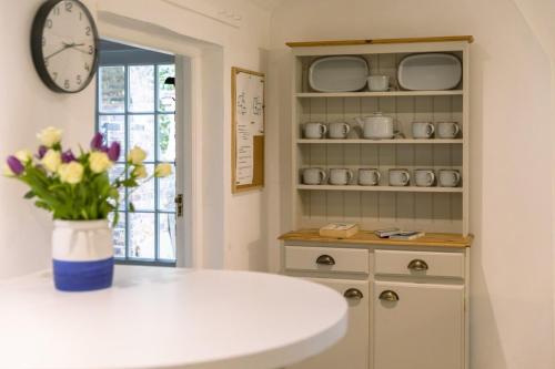 une cuisine avec un comptoir et une horloge au mur dans l'établissement Danny Lodge - Country Cottage Near Brighton by Huluki Sussex Stays, à Hurstpierpoint