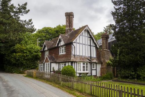 an old house with a fence next to a road at Danny Lodge - Country Cottage Near Brighton by Huluki Sussex Stays in Hurstpierpoint