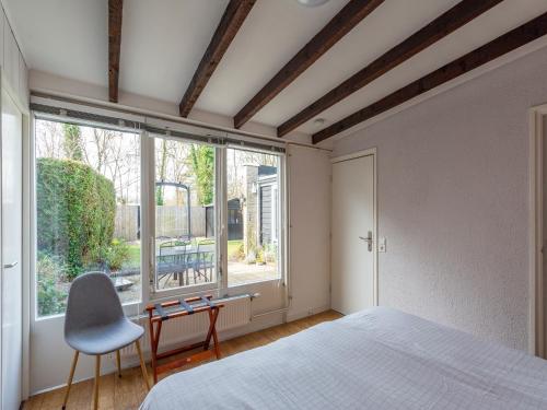 a bedroom with a bed and a chair and a window at Bungalow in Sint Maartenszee near Dunes in Sint Maartensvlotbrug