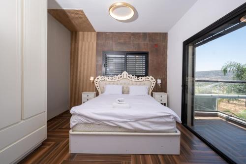a bedroom with a bed and a large window at ויקטוריה - ווילה מהממת עם ממ"ד ובריכה פרטית בכלנית in Kallanit