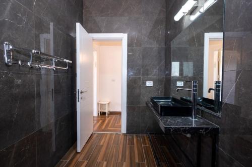 a black bathroom with a sink and a mirror at ויקטוריה - ווילה מהממת עם ממ"ד ובריכה פרטית בכלנית in Kallanit