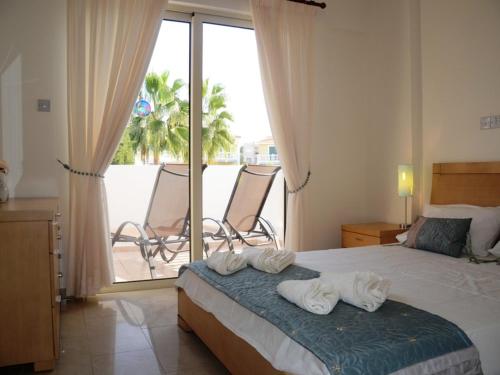 1 dormitorio con 1 cama y balcón con sillas en Vanessa 2 bedroom apartment, en Pafos