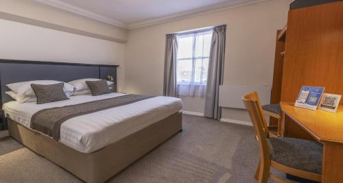 een hotelkamer met een bed, een bureau en een raam bij Best Western Corona Hotel in Londen