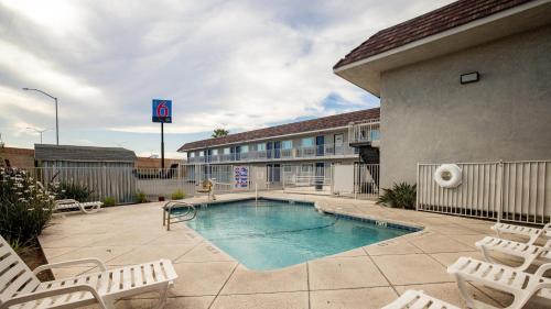 a pool in front of a building with chairs at Motel 6 Ontario, CA - Airport in Ontario